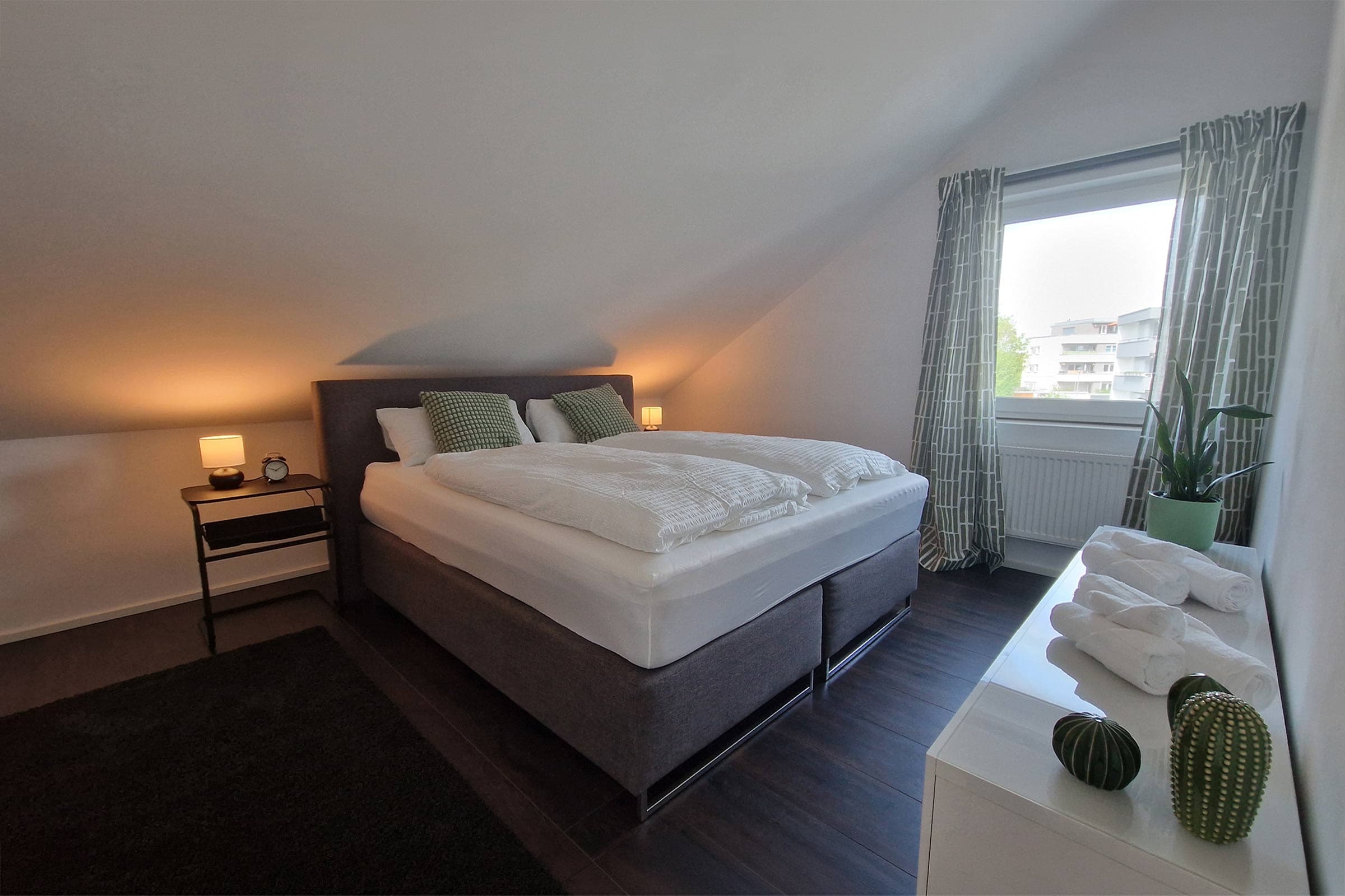 Schlafzimmer mit Kingsize-Boxspringbett und warmer Nachttischbeleuchtung